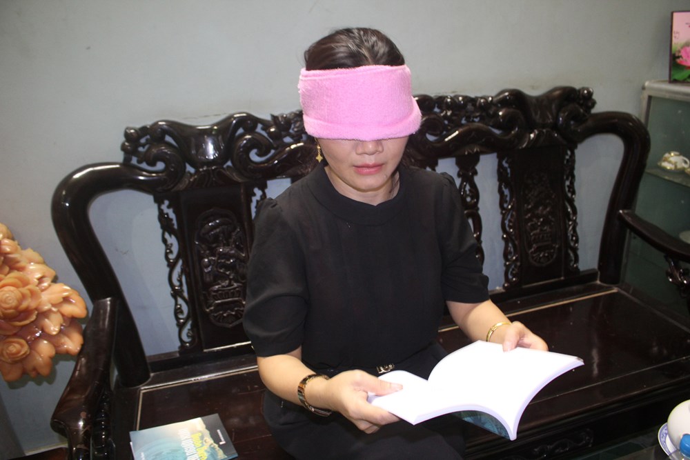 Chị Hoàng Thị Thiêm có thể đọc sách trong khi mắt bị bịt kín (ảnh: kienthuc.net.vn)